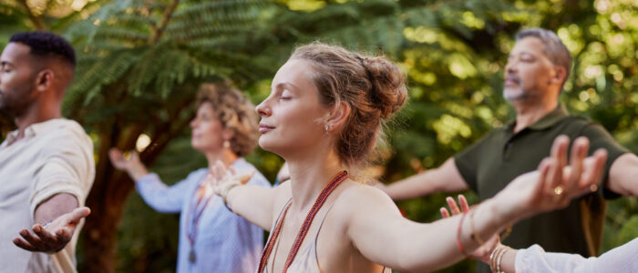 Young woman meditating with a group of diverse people outdoor