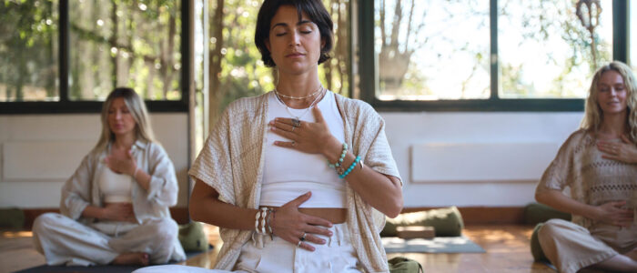 Young women group meditating doing breathing exercises at yoga session.
